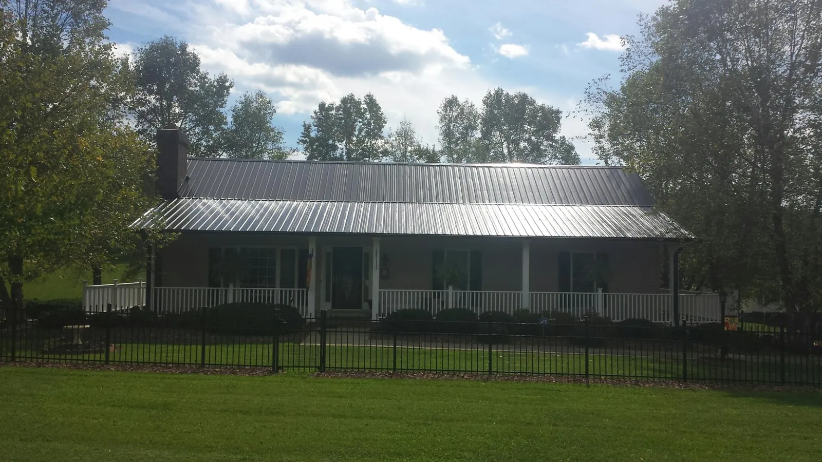 Gray metal roof on a brick ranch with a full width front porch — Gutter Guard Installation work by our crew in Phoenixville