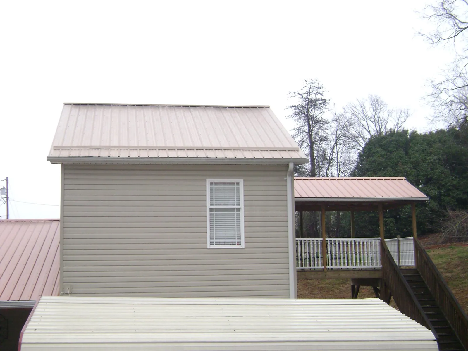 Tan metal roofs on a two story addition and attached porch, from a Roof Replacement job in Phoenixville