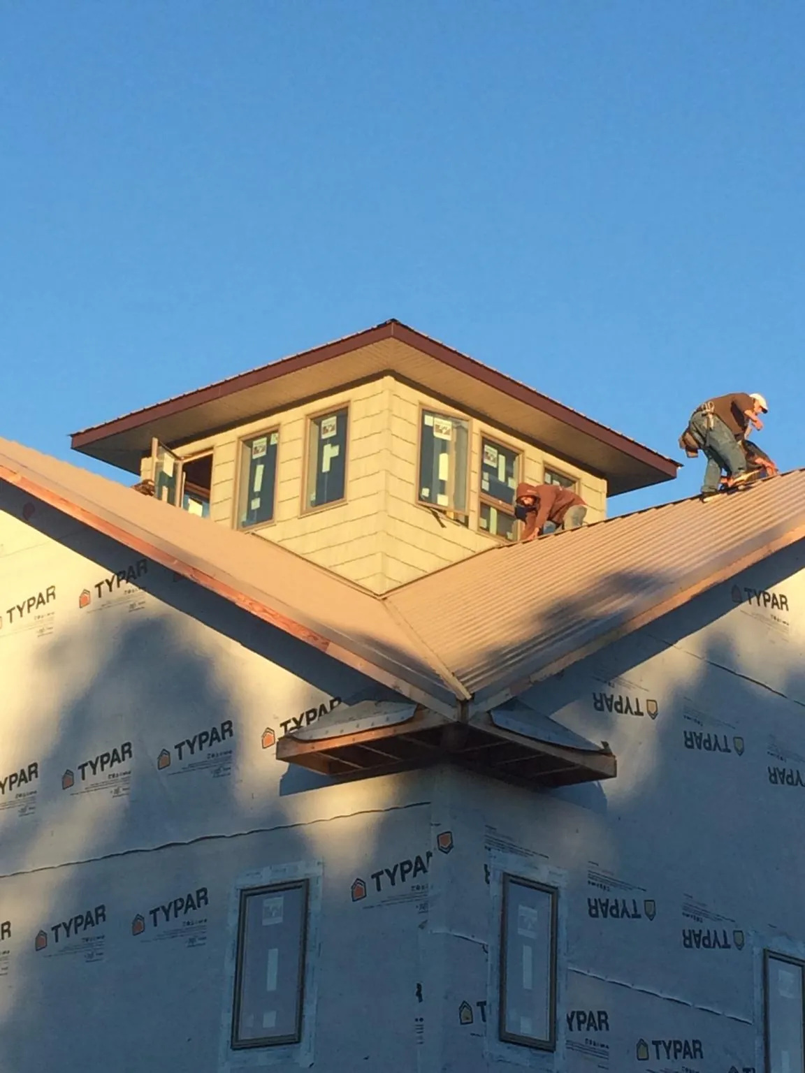 Roofers working around a rooftop cupola on a new metal roof at sunset — Roof Waterproofing in Phoenixville by Roofing Brothers